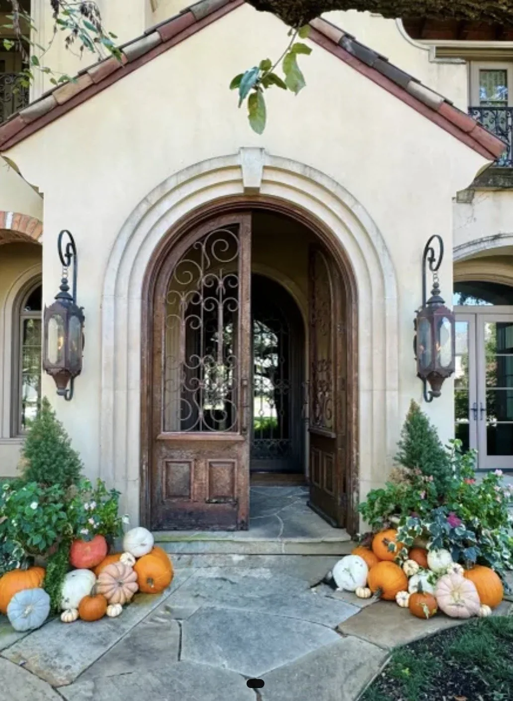 Small front entrance styled with roughly 15 to 20 real uncarved pumpkins beside the door